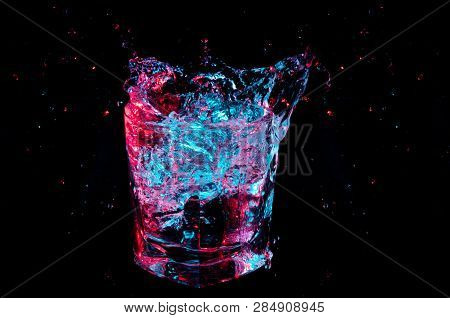 Bright Glowing Blue And Red Splash From A Rocks Glass Isolated On A Black Background