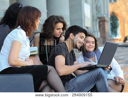 Group Of Fellow Students With Books And Laptop
