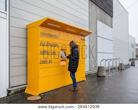 Strasbourg, France - Feb 8, 2018: Young Woman Using Yellow Amazon Locker The Self-service Parcel Del