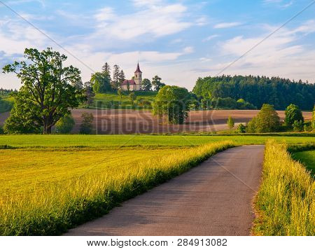 Small Church In The Middle Of Lush Green Spring Landscape On Sunny Day. St. Peter And Pauls Church A