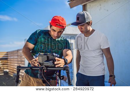 Steadicam Operator And His Assistant Prepare Camera And 3-axis Stabilizer-gimbal For A Commercial Sh