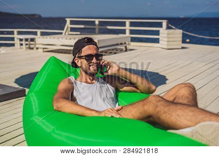 Young Man Enjoying Leisure, Lying On The Air Sofa Lamzac, Near The Sea
