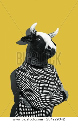 young caucasian man with a cow mask, in black and white, on a yellow background with some blank space on top