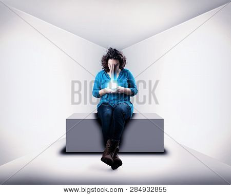 Woman Using Smartphone In White Room. The Concept Of Phone Addiction. Face Absorbed By The Phone.