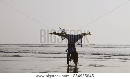 Young Gymnast Woman Doing Handspring On Sandy Beach