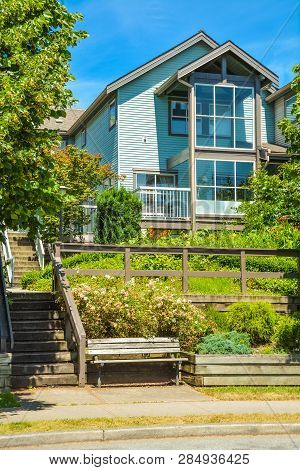 Facade Of Residential House Built On Land Terrace With Wooden Bench In Front