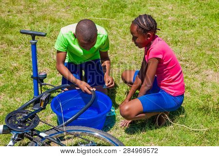 African Children Fixing A Puncture On A Bike