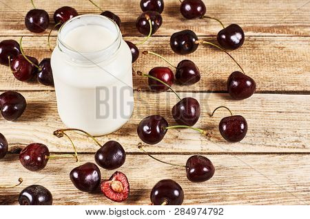 Greek Yoghurt, Opened Cherry With A Ossicle, On A Cherryes And Brown Wooden Background