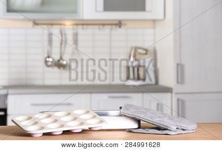 Clean Baking Dish, Muffin Pan And Oven Glove On Table In Kitchen. Space For Text