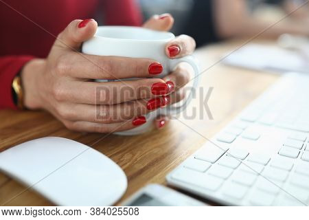 Female Hands With Red Manicure Hold White Cup On Work Table. Work Breaks And Coffee Time Concept