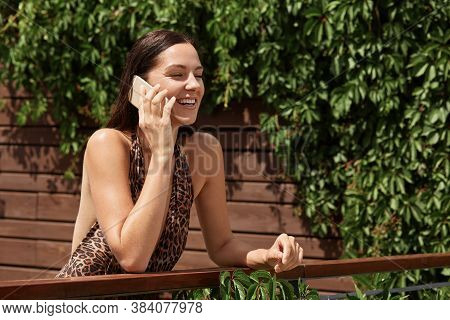 Woman In Bathing Suit With Leopard Print, Talking On Phone With Good Mood And Positive Facial Expres