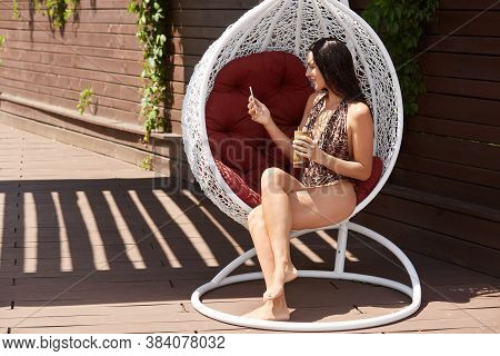 Brunette Lady With Wearing Swimming Suit With Leopard Print Sitting On White Stylish Hanging Chair A