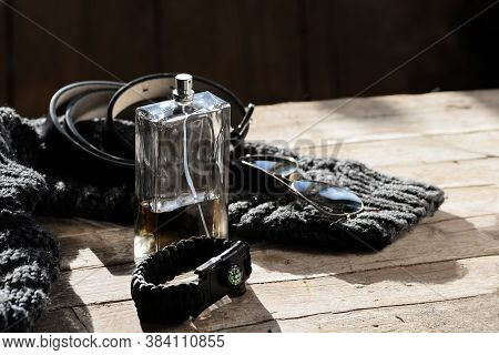 Transparent Bottle, A Black Leather Belt, Glasses, A  Bracelet With A Compass Lie On A Woolen Knitte