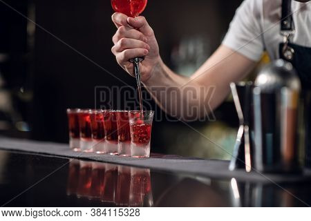 Bartender Pours Red Alcohol Into Shots On The Bar, Bartenders Show.