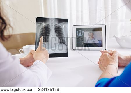 Pulmonologist Checking Lungs X-ray Of Senior Woman And Video Calling Senior Colleague