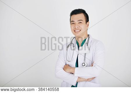 Portrait Of Hapy Smiling Young Vietnamese Doctor Crossing Arms And Looking At Camera, Isolated On Sh