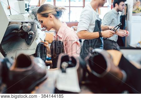 Shoes waiting to be repaired in workshop of cobbler, the shoemaker standing in the background