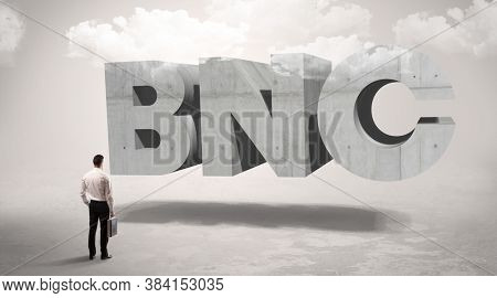Rear view of a businessman standing in front of BNC abbreviation, modern technology concept