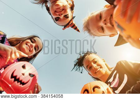 From Below Delighted Children In Costumes Smiling For Camera And Carrying Trick Or Treat Baskets Dur