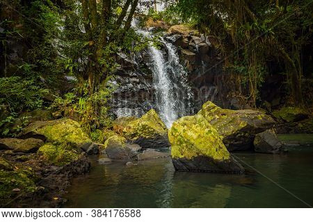 Tropical Landscape. Beautiful Hidden Waterfall In Rainforest. Foreground With Big Stones. Adventure 