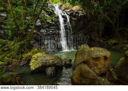 Tropical Landscape. Beautiful Hidden Waterfall In Rainforest. Foreground With Big Stones. Adventure 