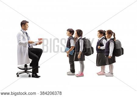 Dentist showing theeth brushing with a model jaw to a group of schoolchildren isolated on white background
