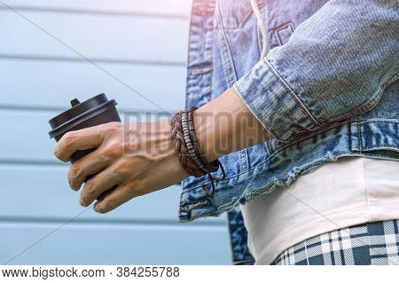 Hippie Woman Wearing Boho Leather Bracelets On A Wrist And Jeans Denim Jacket Holding A Takeaway Pap