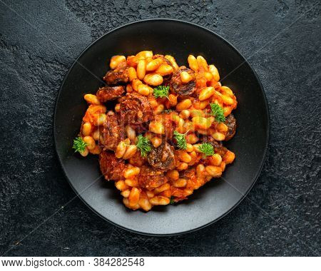 Bean And Chorizo Stew Served In Black Plate With Parsley