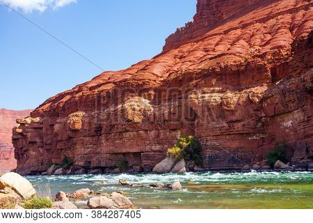 Stormy wide river with rapids and steep banks of red sandstone and cold water. Lee's Ferry is a historic boat ferry across the Colorado River. Arizona. The concept of extreme and photo tourism