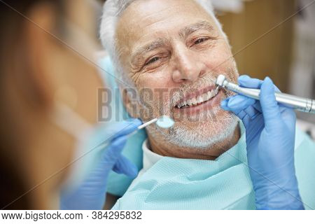 Mirthful Senior Citizen Smiling During A Dental Treatment