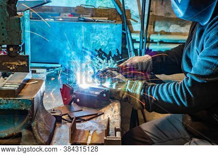 Electric Welding Process. Worker In Welding Mask. Yellow Sparks Fly To The Sides. Bright White.