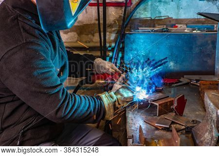 Electric Welding Process. Worker In Welding Mask. Yellow Sparks Fly To The Sides. Bright White And B