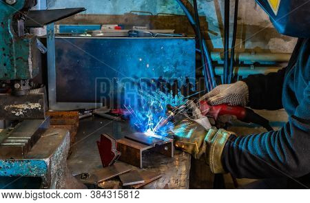 Electric Welding Process. Worker In Welding Mask. Yellow Sparks Fly To The Sides. Bright White And B