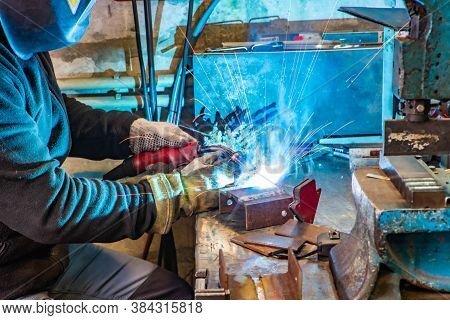 Electric Welding Process. Worker In Welding Mask. Yellow Sparks Fly To The Sides. Bright White.