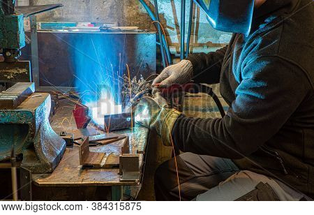 Electric Welding Process. Worker In Welding Mask. Yellow Sparks Fly To The Sides. Bright White.