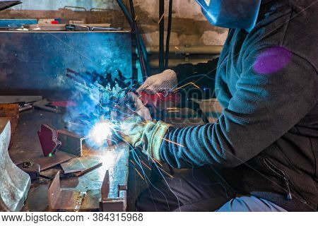 Electric Welding Process. Worker In Welding Mask. Yellow Sparks Fly To The Sides. Bright White.