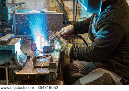 Electric Welding Process. Worker In Welding Mask. Yellow Sparks Fly To The Sides. Bright White.