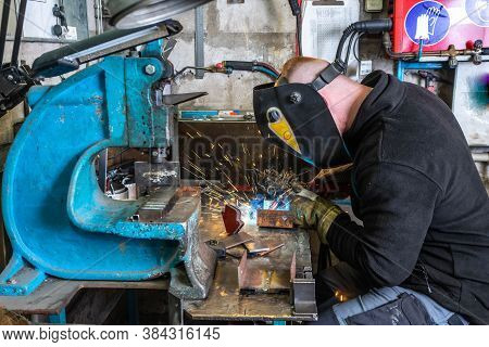 Electric Welding Process. Worker In Welding Mask. Yellow Sparks Fly To The Sides.