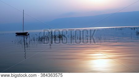 Sunrise Over The Lake. Boat Floating On The Calm Water Under Amazing Sunset.