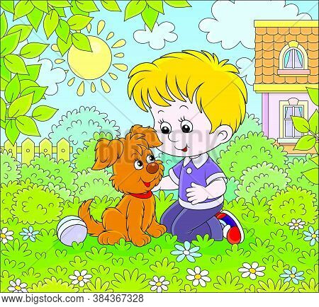 Little Boy Playing With A Small Brown Pup Among Flowers On Green Grass Of A Lawn In Front Of His Hou