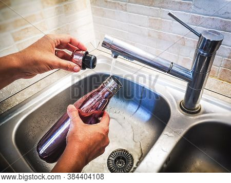 Hand With Aluminum Eco Friendly Bottle Pour Tap Water From The Sink To Reduce Plastic Usage