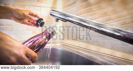 Hand With Aluminum Eco Friendly Bottle Pour Tap Water From The Sink To Reduce Plastic Usage