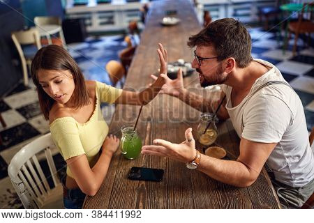 Young couple talking and arguing in a cafe
