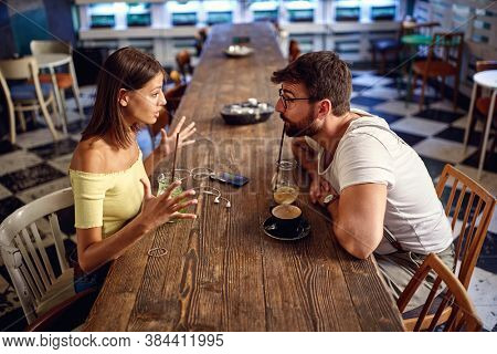 Young couple having drink and discussing in a cafe