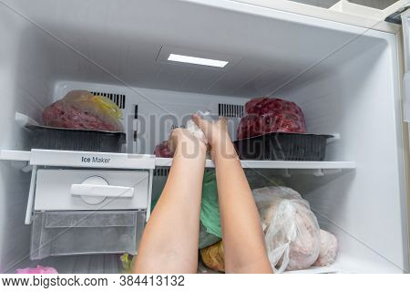 The Woman Takes Out Frozen Food From The Freezer.