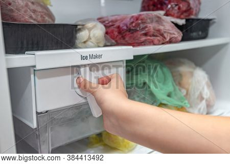 The Girl Switches The Freezer Icemaker To Serve Ice Cubes.