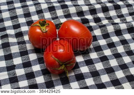 juicy red tomatoes in table cloth . caro background