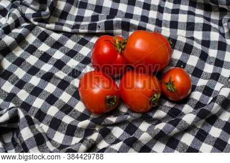 juicy red tomatoes in table cloth . caro background
