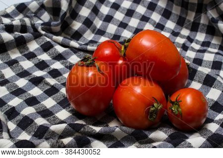 juicy red tomatoes in table cloth . caro background