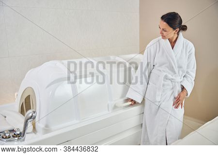Curious Pretty Woman Looking At The Spa Capsule And Smiling